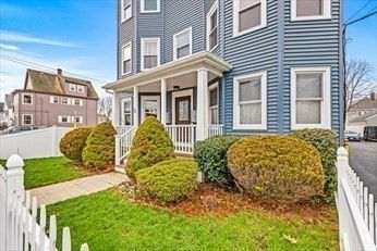 Front view of a multi-story residential building with blue siding and a small porch.