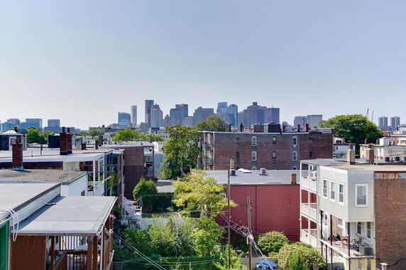 Wide-angle view of rooftop buildings with a city skyline in the background.