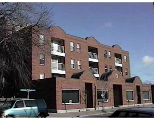 Front view of a multi-story brick apartment building with balconies.