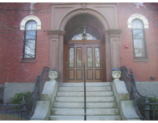 Front view of a brick building with an arched entrance and stairway.