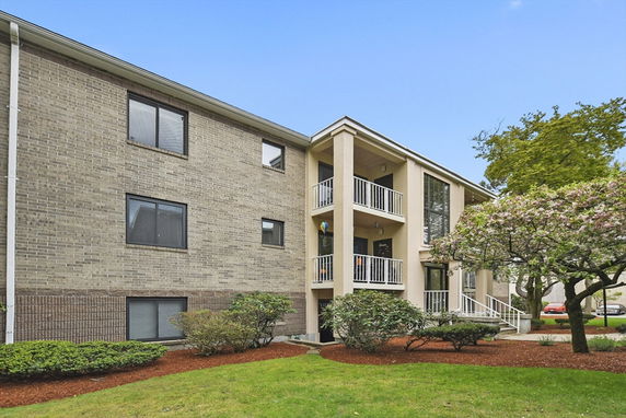 Front view of a multi-story apartment building with balconies and brick exterior.