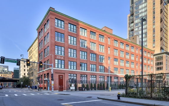 Front view of a multi-story red brick building with large windows.