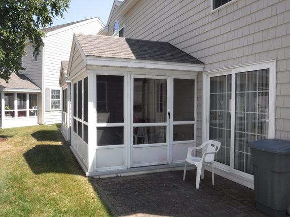 Backyard view of a house with a screened porch and glass sliding doors.