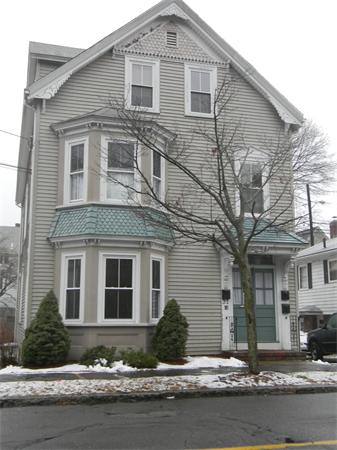 Front view of a multi-story house with decorative trim and large windows.