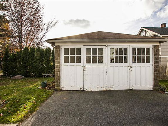 Front view of a single-story garage with double white doors.