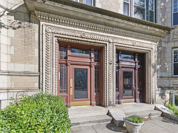 Front view of a building entrance with ornate architectural details and two doors.
