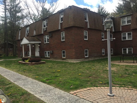 Front view of a brick apartment building with multiple windows and a small entry porch.