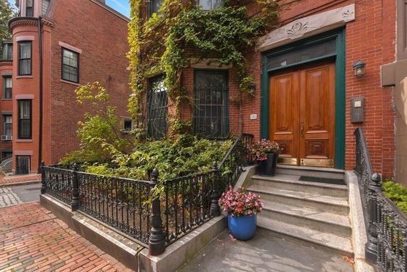 Front view of a brick building with a wooden door and ivy-covered facade.