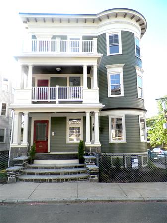 Front view of a multi-story house with balconies and a red door.