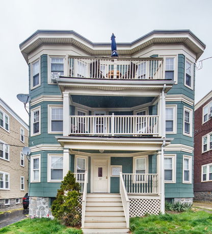 Front view of a multi-story house with balconies and a main entrance.