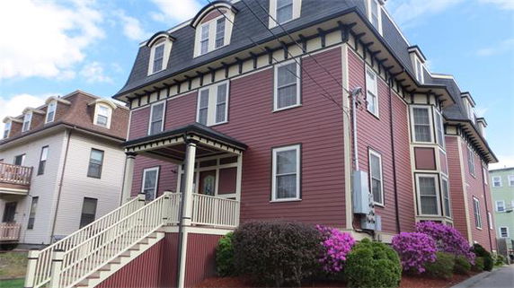 Front view of a large two-story house with multiple dormer windows and red siding.