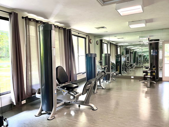 Interior view of a gym area with exercise equipment and mirrored walls.