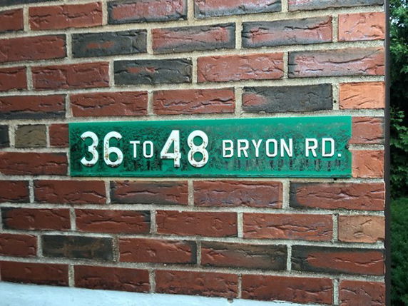 Exterior brick wall with a green address sign reading '36 to 48 Bryon Rd.'