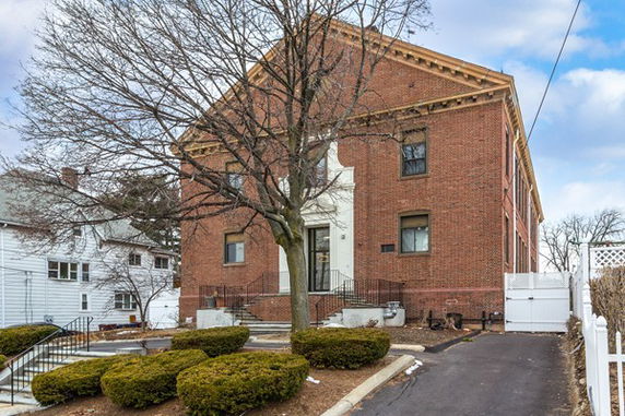 Front view of a brick building with a classical facade and entrance steps.