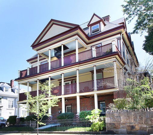 Front view of a multi-story house with balconies and a sloped roof.