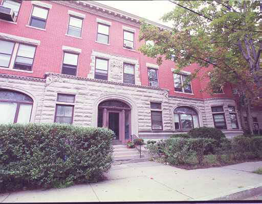 Front view of a multi-story brick building with arched entrance and stone details.