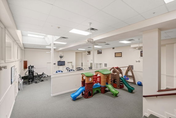 Indoor play area featuring colorful play structures and exercise equipment.