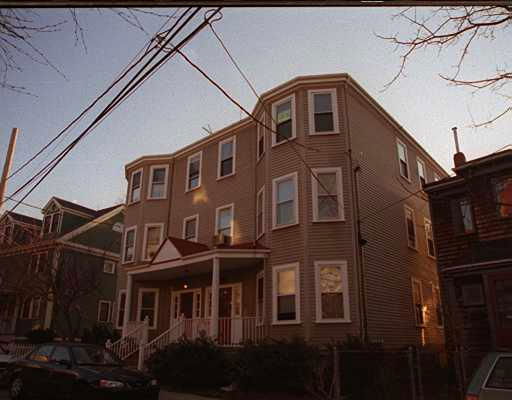Front view of a multi-story residential building with a porch and several windows.