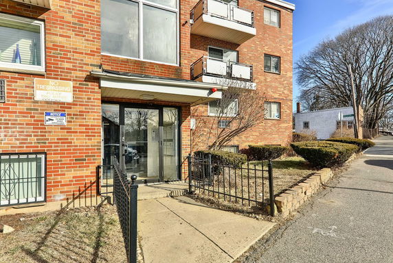 Front view of a brick apartment building with a glass entrance and balconies.