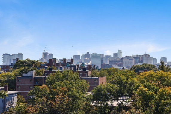 Panoramic view of a city skyline with various buildings and greenery in the foreground.