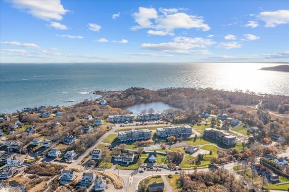 Wide-angle panoramic view of coastal area with ocean and residential buildings.