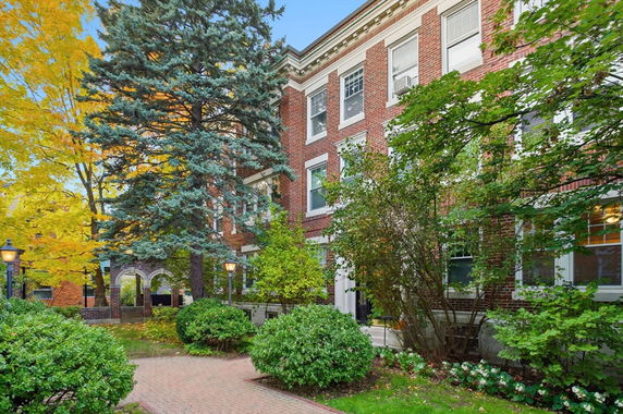 Front view of a multi-story brick building with large windows and a landscaped entrance.