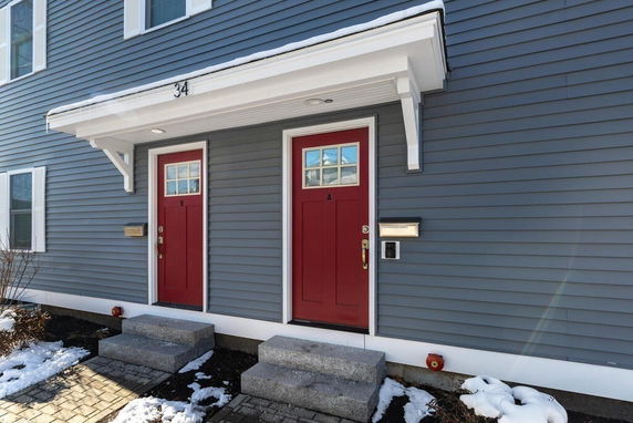 Front view of a house with two red doors and gray siding.