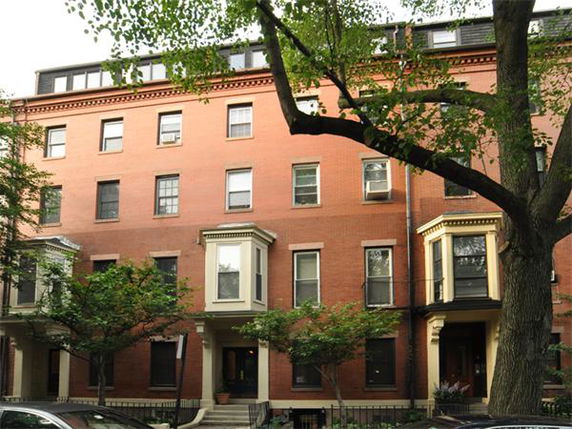 Front view of a multi-story brick building with bay windows.