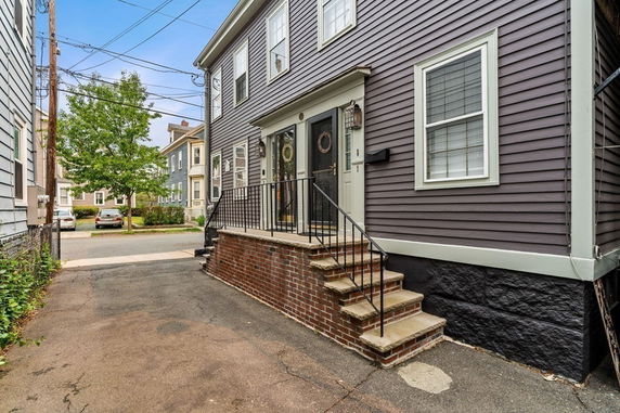 Front view of a two-story house with a small stoop and brick stairs.