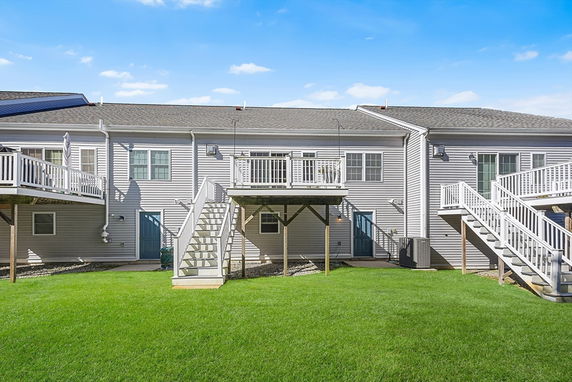 Rear view of a multi-story house with exterior staircases leading to upper decks.