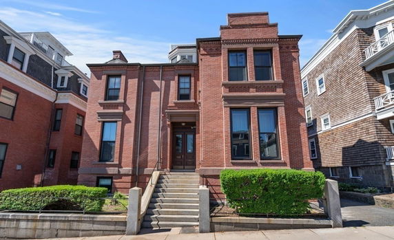 Front view of a brick two-story building with a central staircase and large windows.