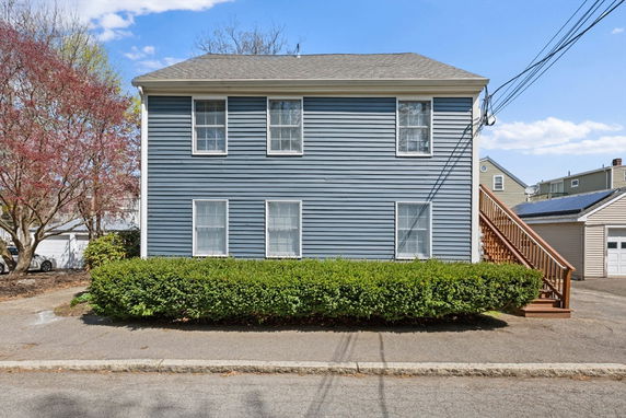 Front view of a two-story house with blue siding and exterior stairs.