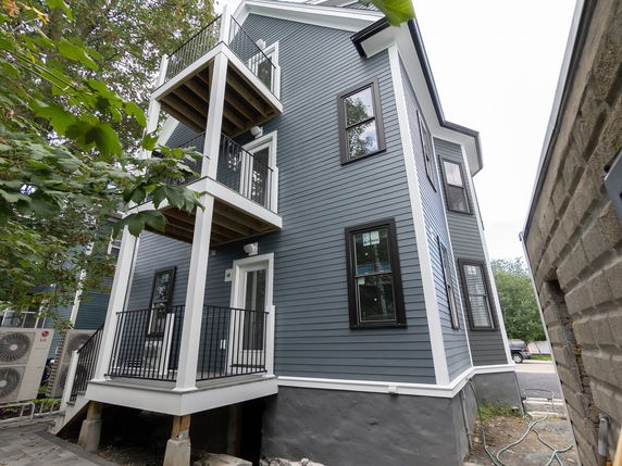 Side view of a multi-story house with balconies and blue siding.