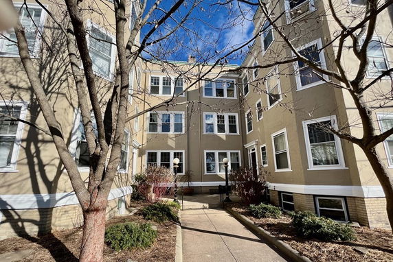 Front view of a multi-story residential building with multiple windows and a pathway leading to the entrance.