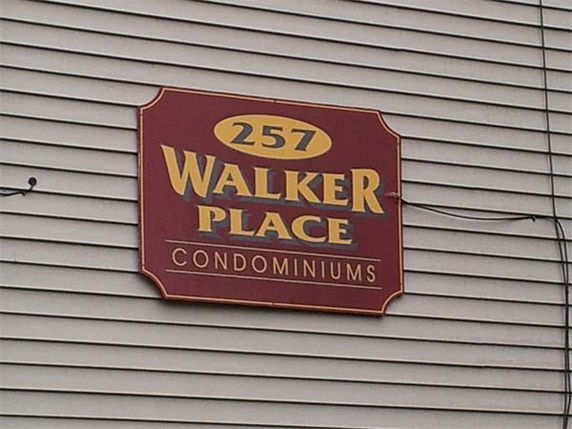 Sign for Walker Place Condominiums on a beige building exterior.