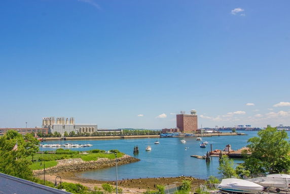 Panoramic view of a waterfront with buildings and boats on a clear day.