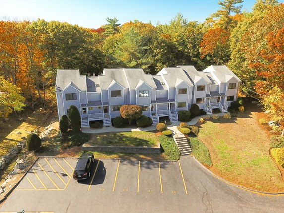 Front view of a multi-unit townhouse building with a paved parking area in front.