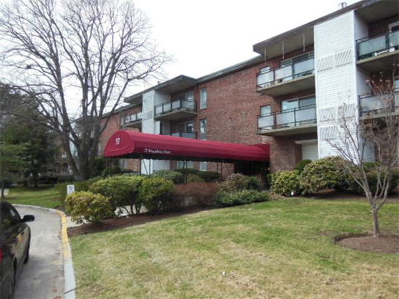 Front view of a multi-story apartment building with balconies and a covered entrance.