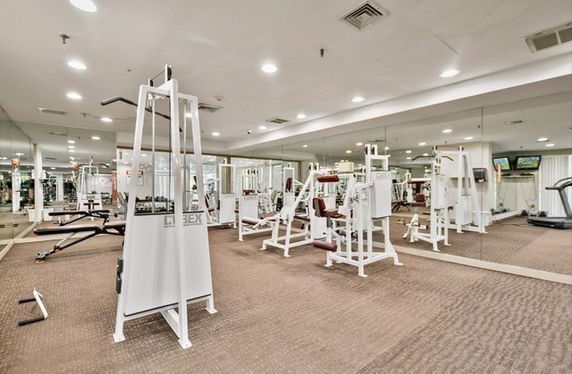 Interior of a gym area with exercise equipment and large mirrors.