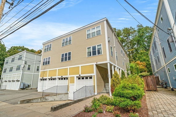 Front view of a multi-story building with garages on the ground level.