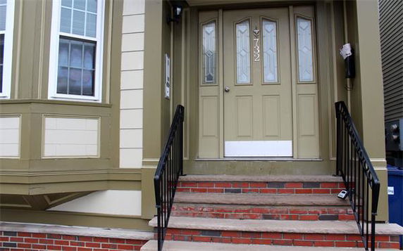 Front view of a house entrance with a staircase leading to a door.