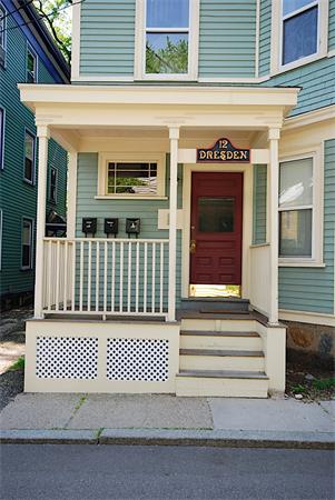 Front view of a multi-story house with a small porch and a red door.