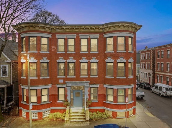 Front view of a three-story brick building with multiple windows.
