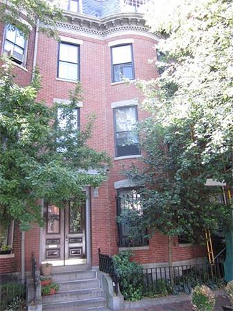 Front view of a multi-story brick house with large windows and a staircase leading to the entrance.