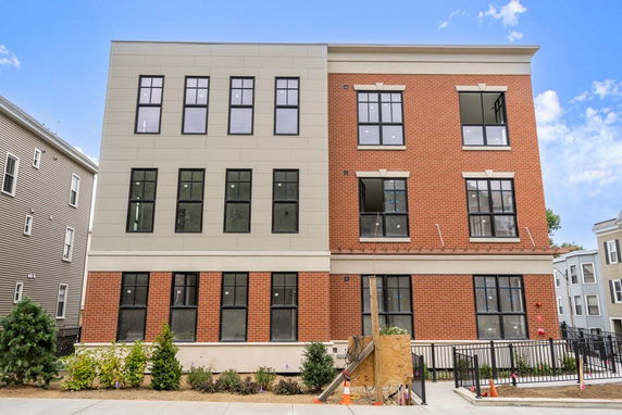 Front view of a three-story modern building with a combination of brick and panel siding.