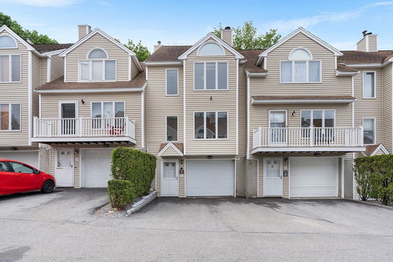 Front view of a multi-story townhouse with garage and balconies.