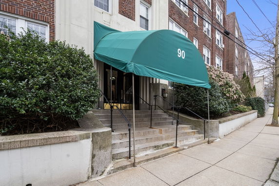 Entrance of a brick building with a green awning and steps leading up to the door.