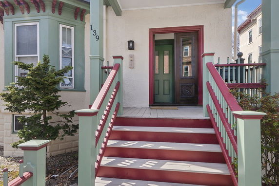 Front view of a house with stairs leading to the entrance and decorative trim.