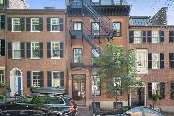 Front view of a multi-story brick building with fire escape.