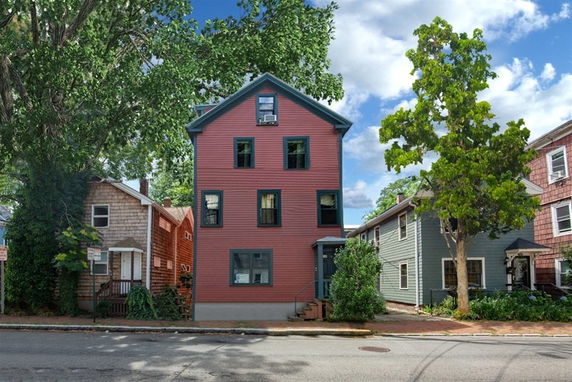 Front view of a three-story house with a red exterior and green trim.